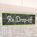 Natural Collection's wayfingding hanging department sign that has "RX Drop-off," digitially printed in white text and on PVC