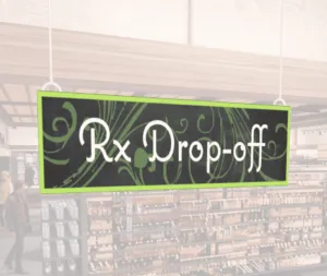 Natural Collection's wayfingding hanging department sign that has "RX Drop-off," digitially printed in white text and on PVC