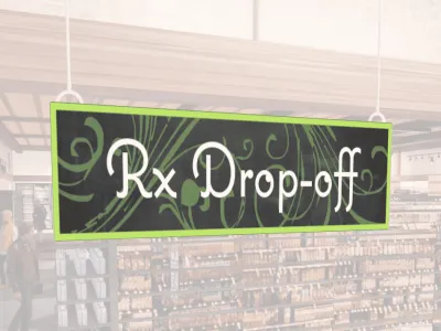 Natural Collection's wayfingding hanging department sign that has "RX Drop-off," digitially printed in white text and on PVC