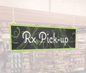 Natural Collection's wayfingding hanging department sign that has "RX Pick-up," digitially printed in white text and on PVC.